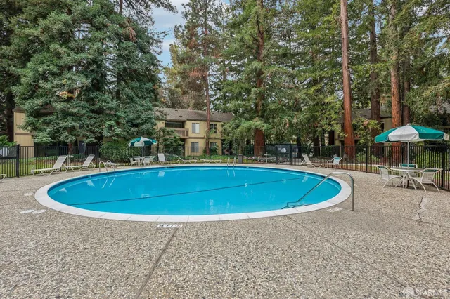 a view of a swimming pool with lawn chairs under an umbrella