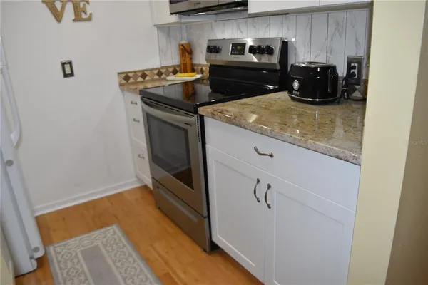 a kitchen with a sink and a stove with wooden floor