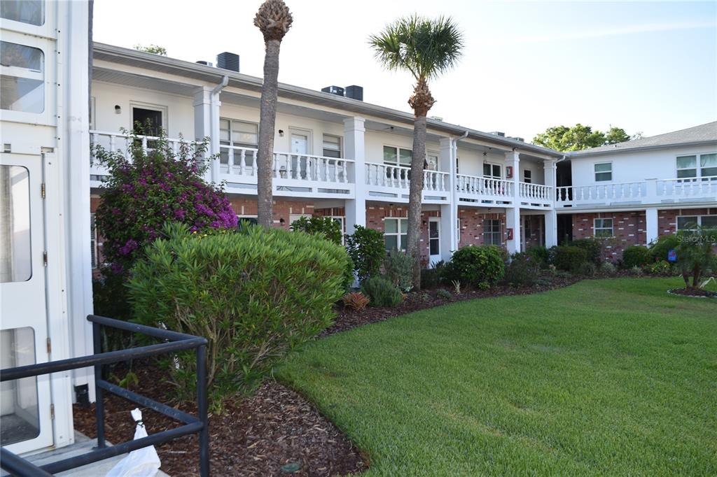 4746 Azalea Drive, Unit 208C New Port Richey, FL 34652 - Photo 44 of 56 a view of a house with a yard and potted plants