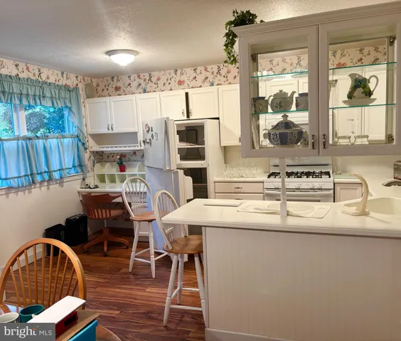 a kitchen with stainless steel appliances granite countertop a sink a microwave refrigerator and a stove with wooden floor