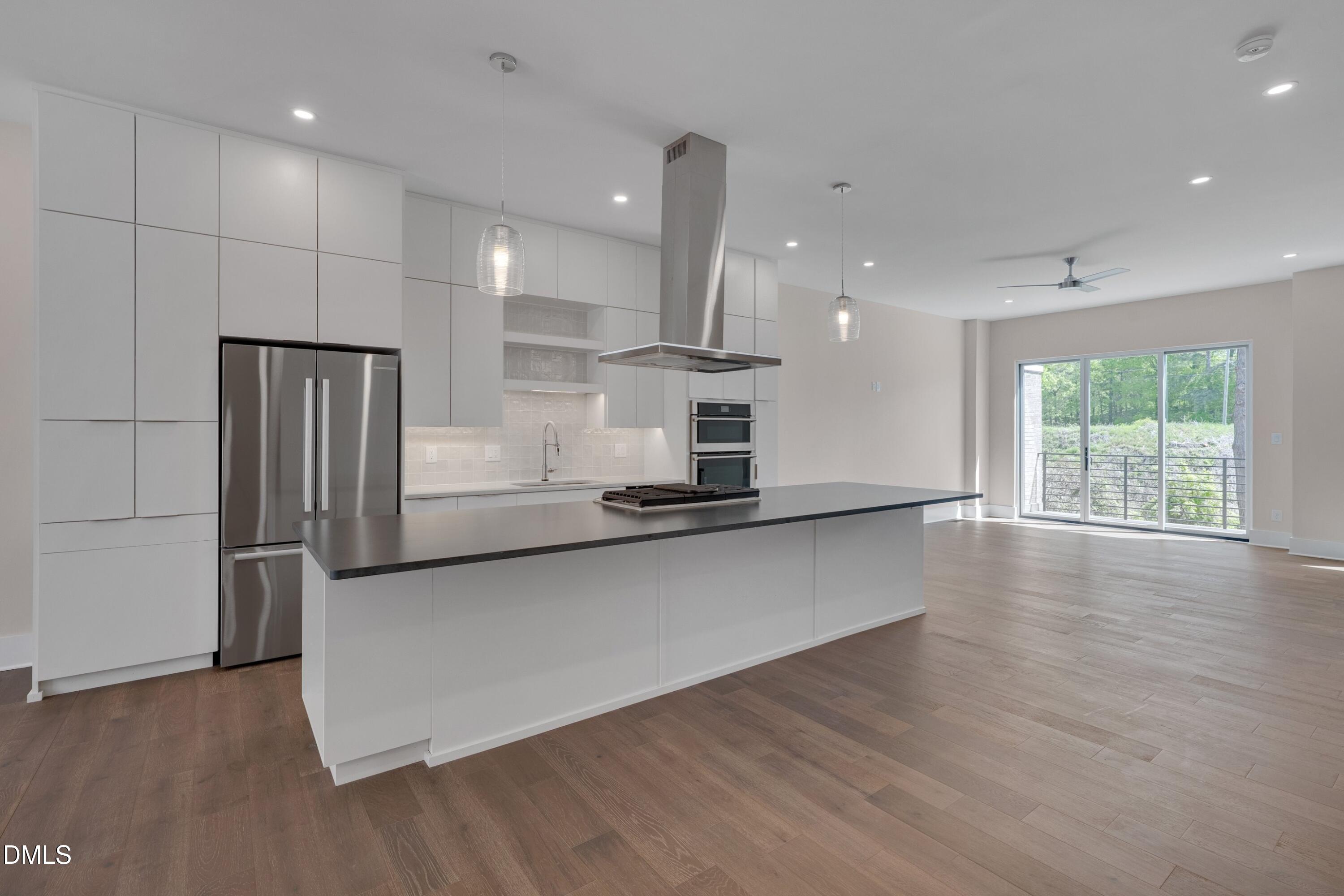 1014 Manor Way Durham, NC 27701 - Photo 8 of 38 a large kitchen with stainless steel appliances a large counter top a wooden floors and a large window