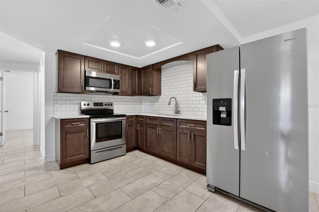 10914 Leeds Road Port Richey, FL 34668 - Photo 5 of 24 a kitchen with stainless steel appliances granite countertop a refrigerator sink and stove