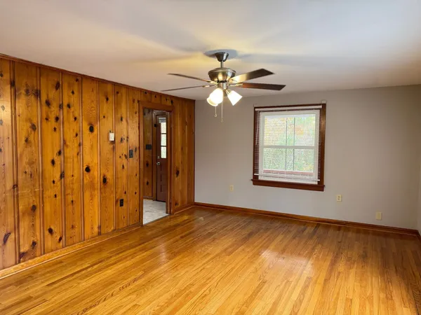 a view of an empty room with window and wooden floor