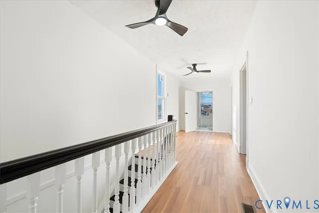 a view of a hallway with wooden floor and a chandelier