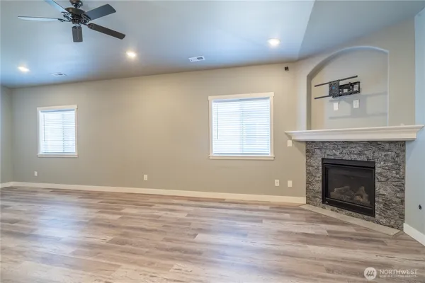 an empty room with windows fireplace and wooden floor