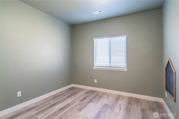 an empty room with wooden floor and painting on the wall