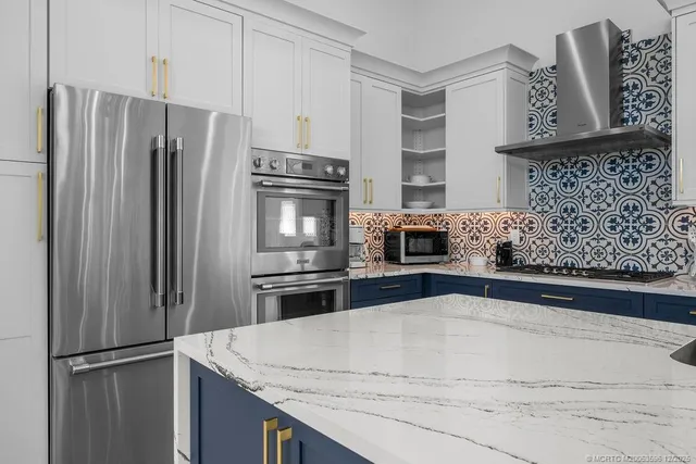 a kitchen with stainless steel appliances kitchen island granite countertop a refrigerator and a sink