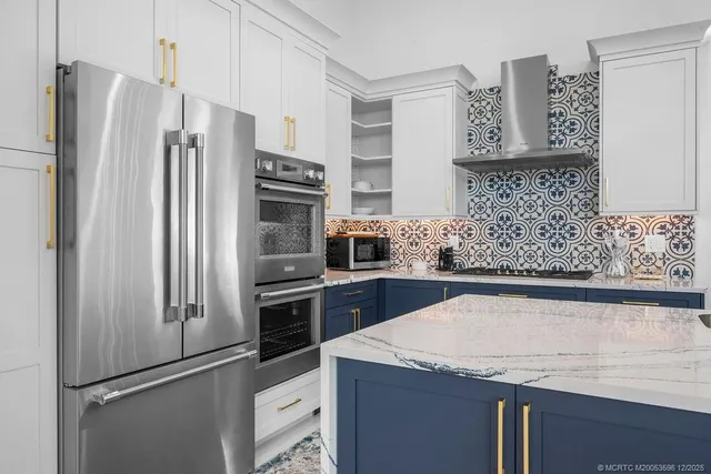 a kitchen with stainless steel appliances granite countertop a refrigerator a sink a stove a dining table and chairs