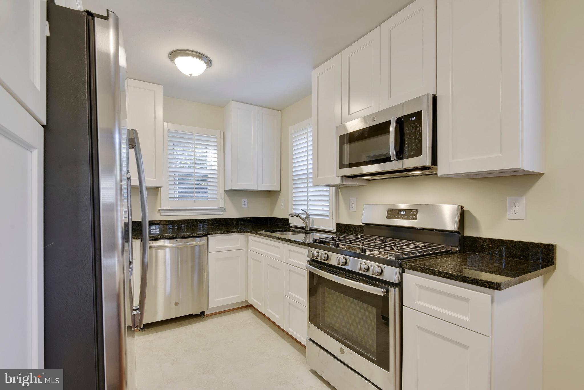 10209 Carson Place Silver Spring, MD 20901 - Photo 7 of 27 a kitchen with stainless steel appliances granite countertop white cabinets a microwave oven a sink and dishwasher with wooden floor