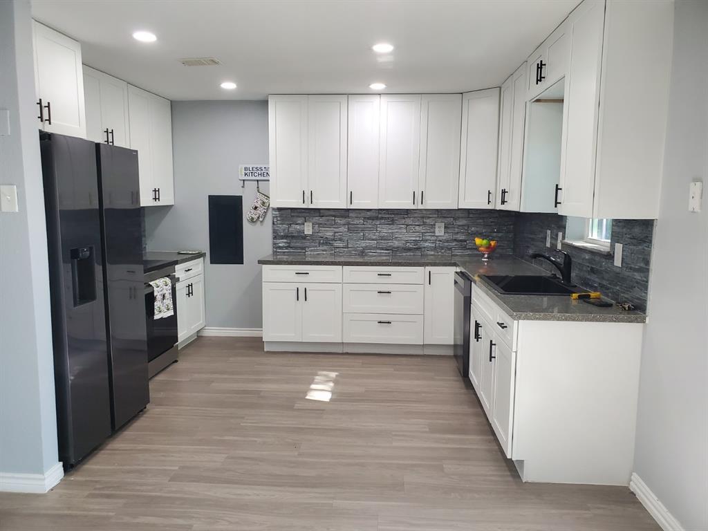 206 Springbranch Drive Garland, TX 75043 - Photo 6 of 12 a kitchen with granite countertop a refrigerator a sink and white cabinets