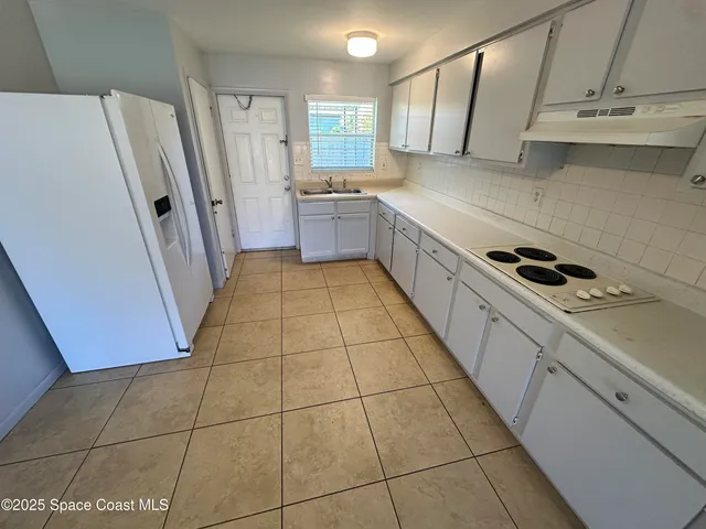 a kitchen with a sink a refrigerator and cabinets