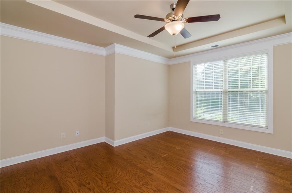 449 Privet Circle Suwanee, GA 30024 - Photo 4 of 9 an empty room with wooden floor ceiling fan and windows