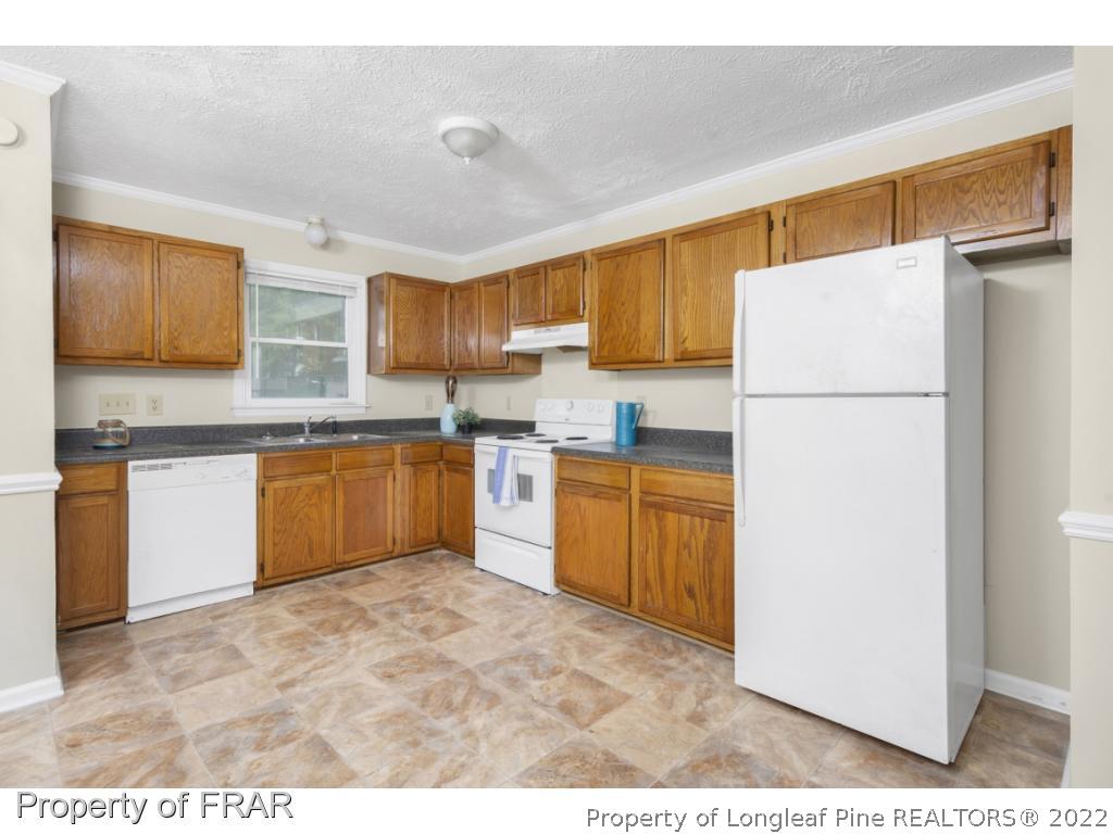 6549 Rhemish Drive Fayetteville, NC 28304 - Photo 11 of 27 a kitchen with granite countertop a sink stainless steel appliances and white cabinets