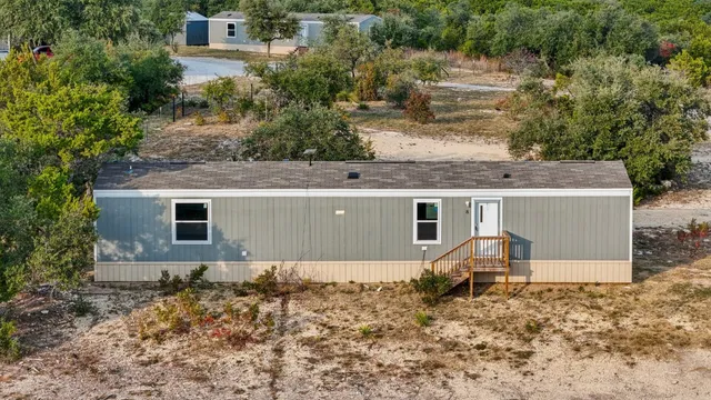 an aerial view of house with yard and trees in the background