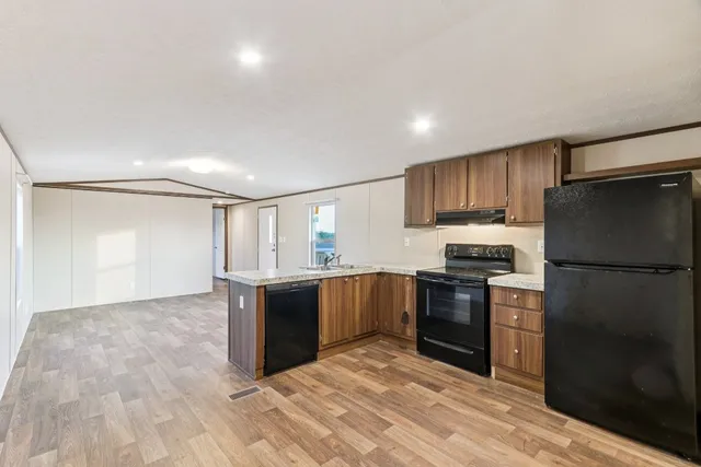 a kitchen with granite countertop a refrigerator and a stove top oven