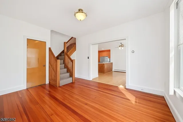 a large white kitchen with wooden floor and a window