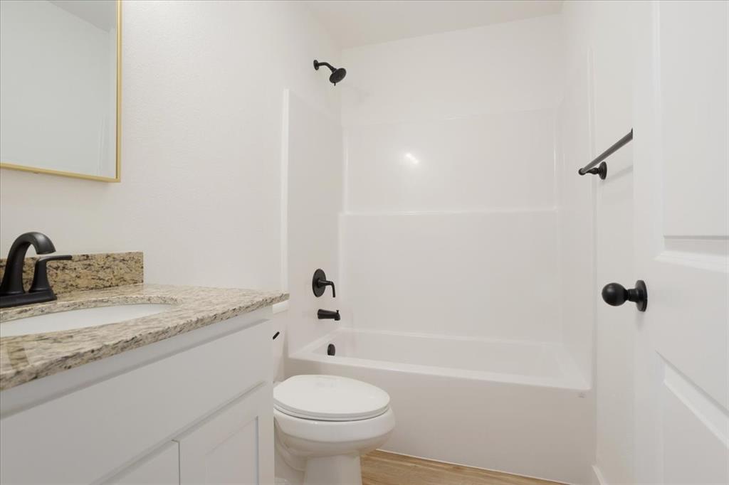 2408 Miller Street Denison, TX 75020 - Photo 20 of 26 a bathroom with a granite countertop sink toilet and shower