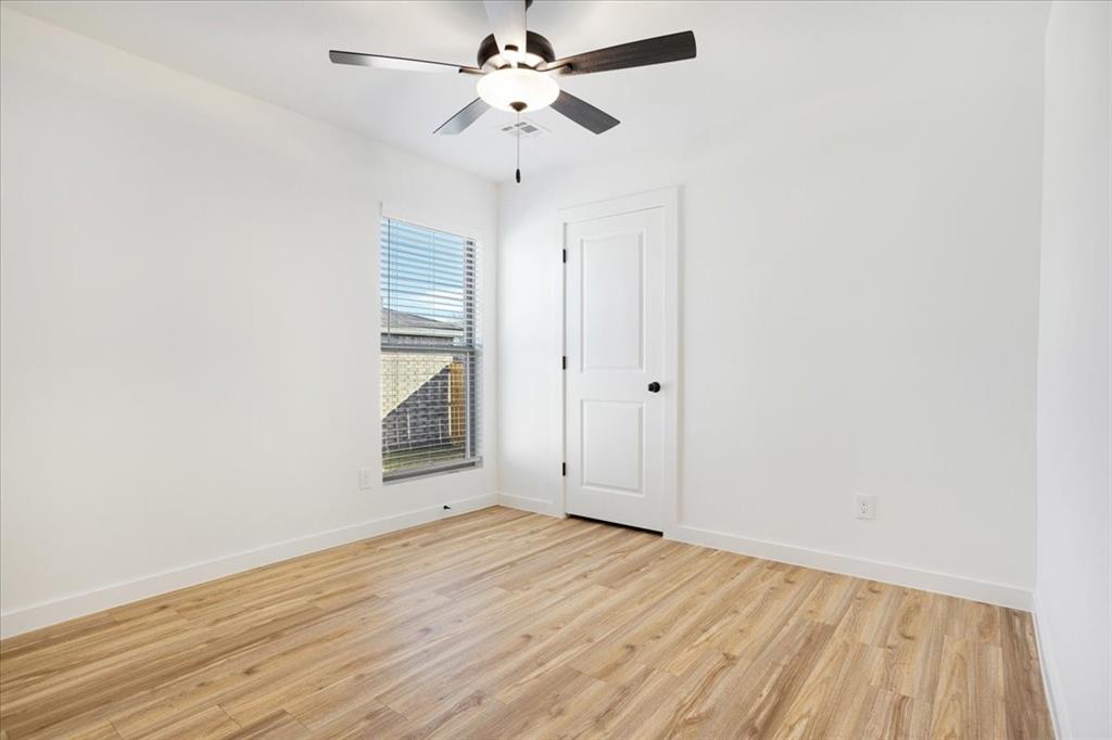 2408 Miller Street Denison, TX 75020 - Photo 21 of 26 an empty room with wooden floor ceiling fan and windows