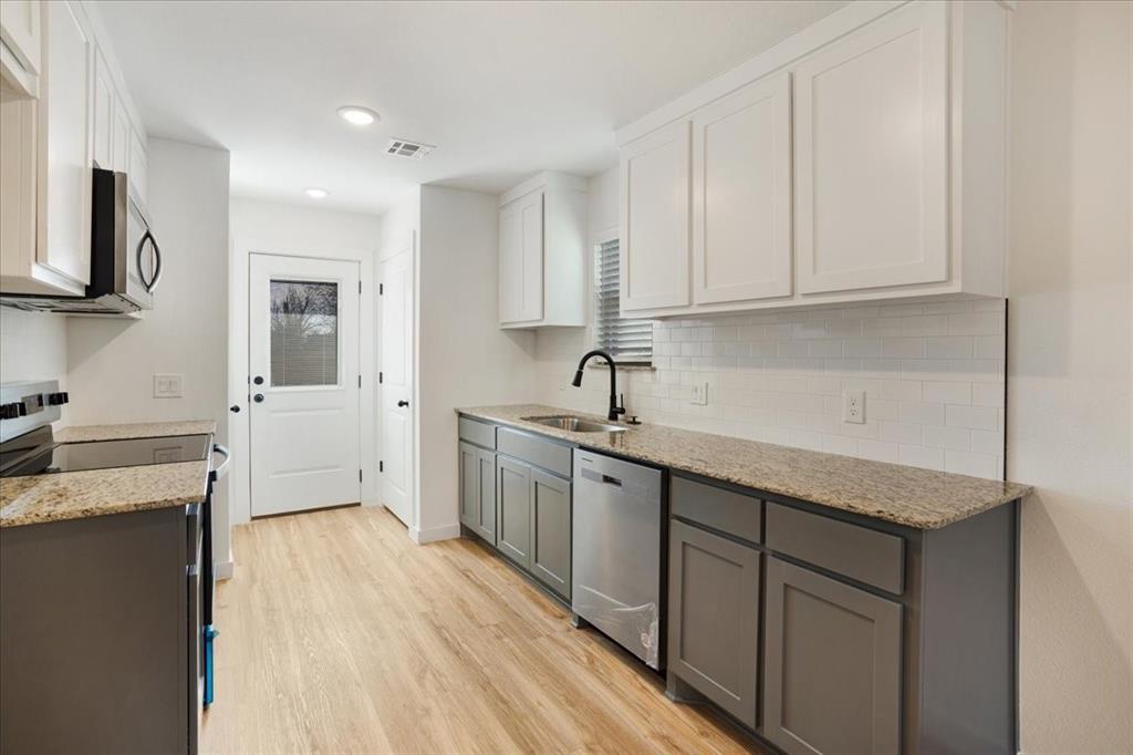 2408 Miller Street Denison, TX 75020 - Photo 10 of 26 a kitchen with granite countertop white cabinets and white appliances
