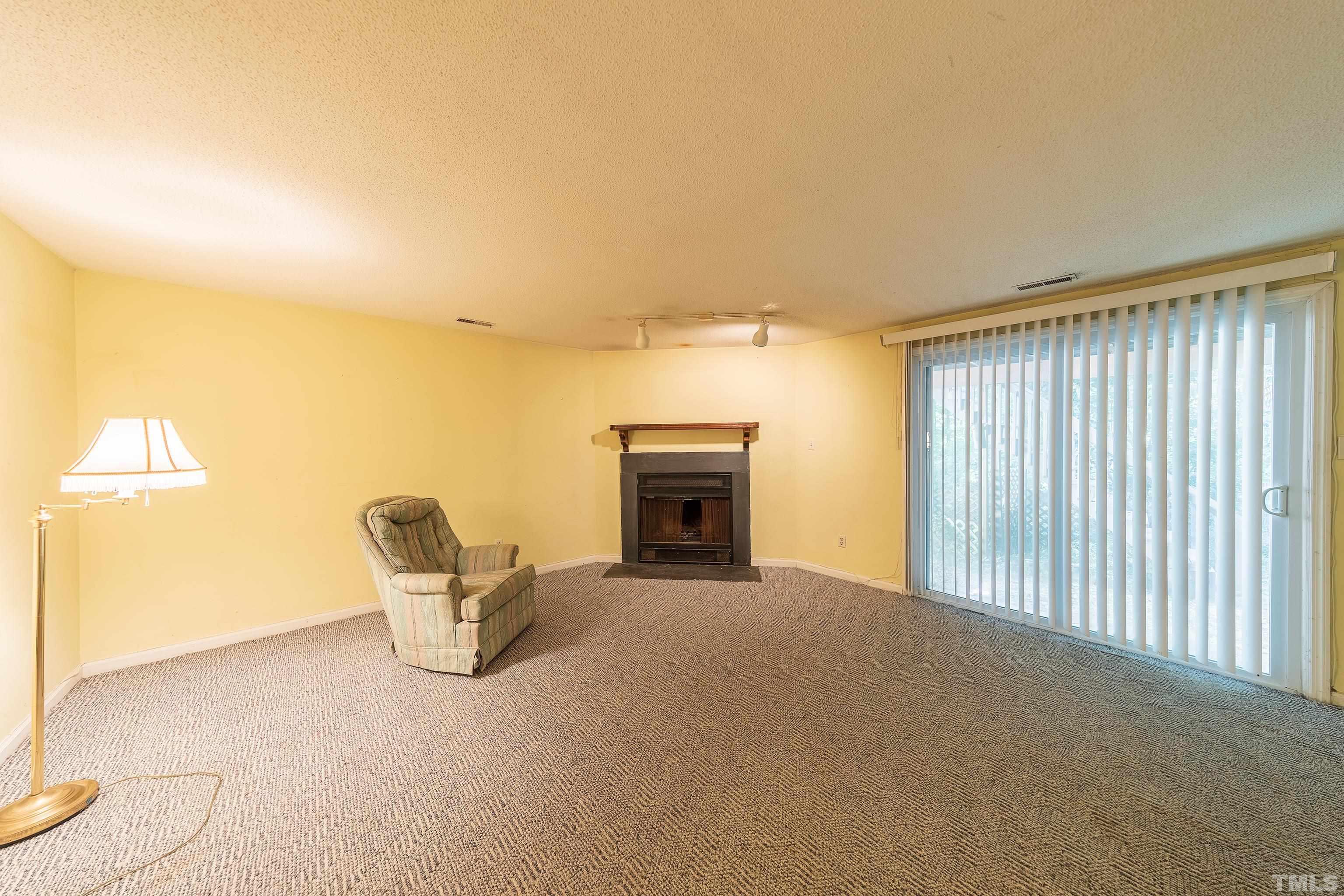 7328 Summerland Drive Raleigh, NC 27612 - Photo 11 of 22 a view of an empty room with a fireplace and a window