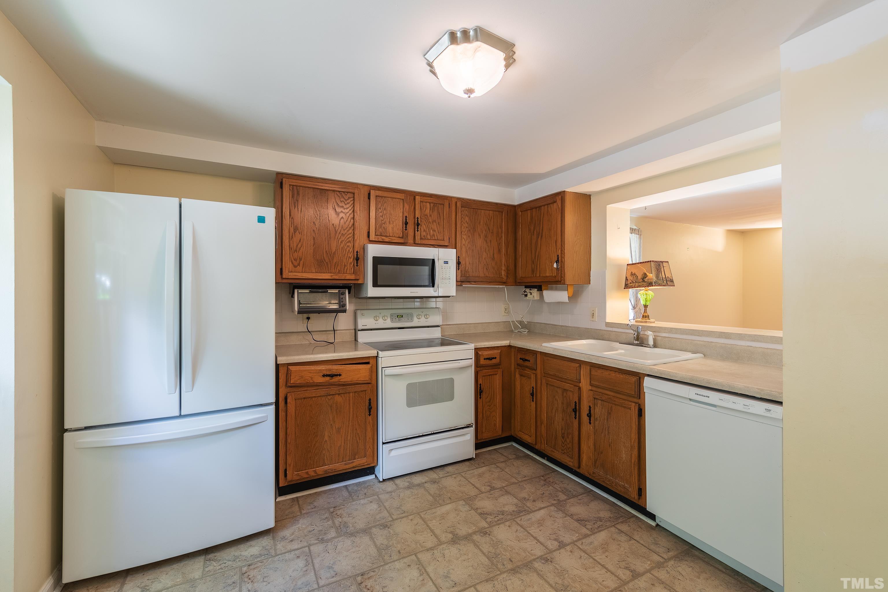 7328 Summerland Drive Raleigh, NC 27612 - Photo 4 of 22 a kitchen with stainless steel appliances granite countertop white refrigerator stove a sink and dishwasher