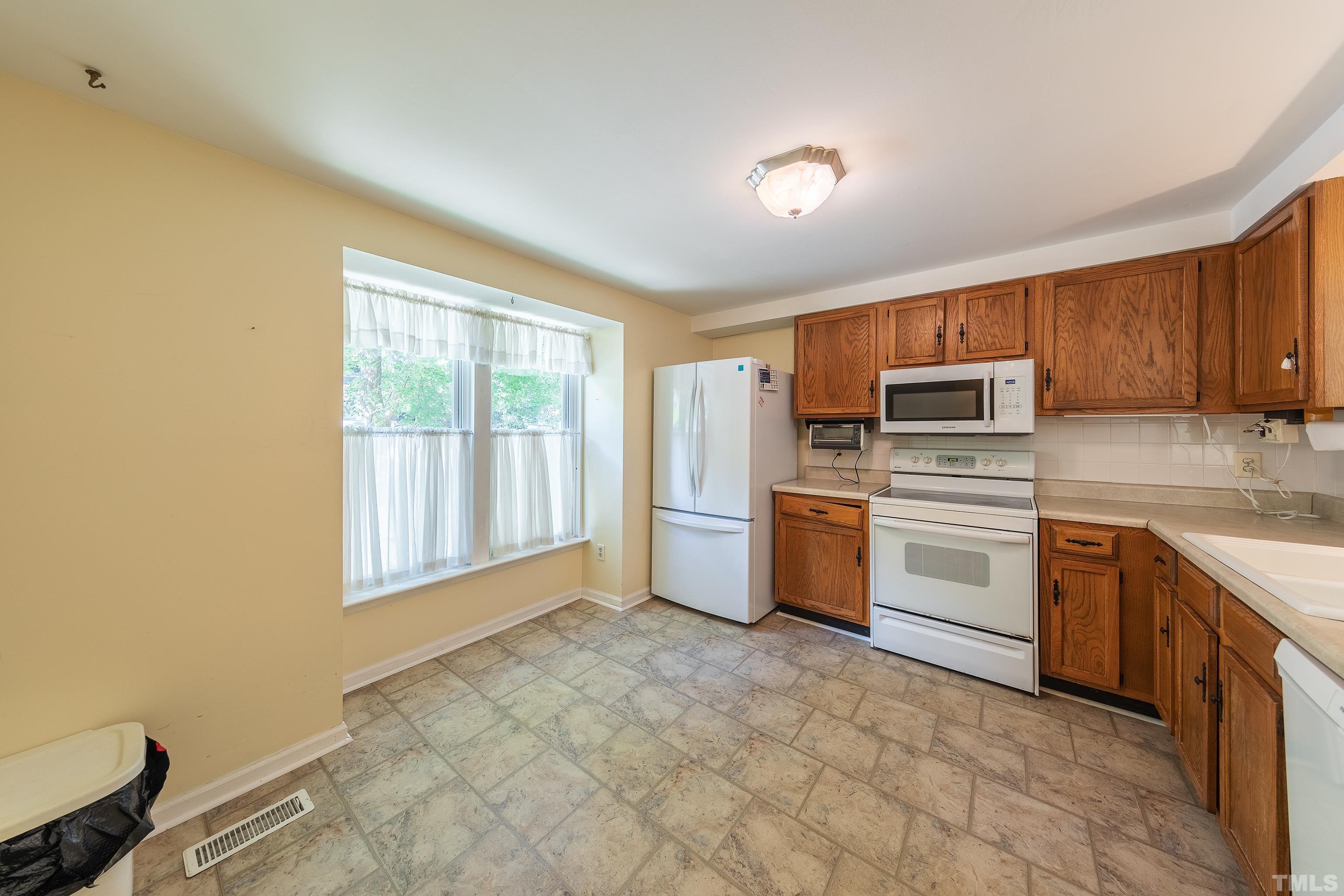7328 Summerland Drive Raleigh, NC 27612 - Photo 5 of 22 a kitchen with stainless steel appliances a stove sink and microwave