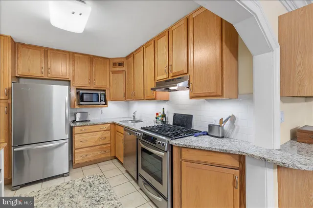a kitchen with stainless steel appliances granite countertop a refrigerator sink stove microwave and cabinets