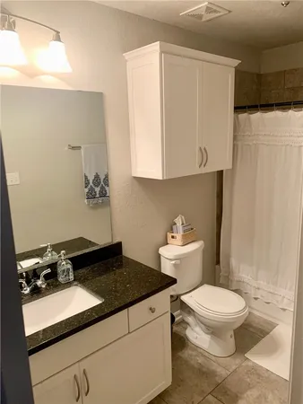 a bathroom with a granite countertop sink and a toilet