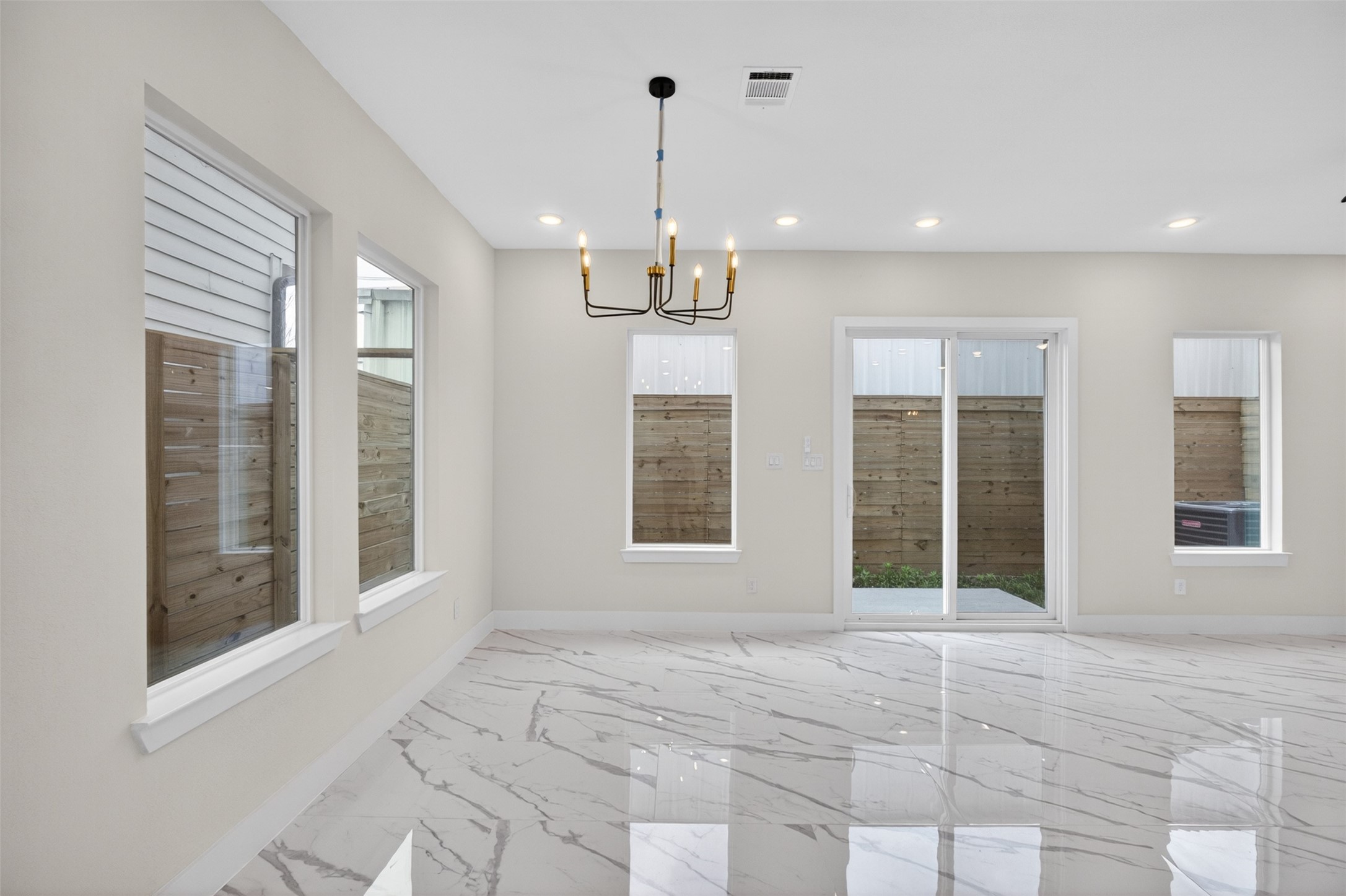 5906 St Augustine Street, Unit F Houston, TX 77021 - Photo 3 of 34 Open living and dining area with glossy marble-look flooring, multiple windows, and sliding doors to the outdoor space.