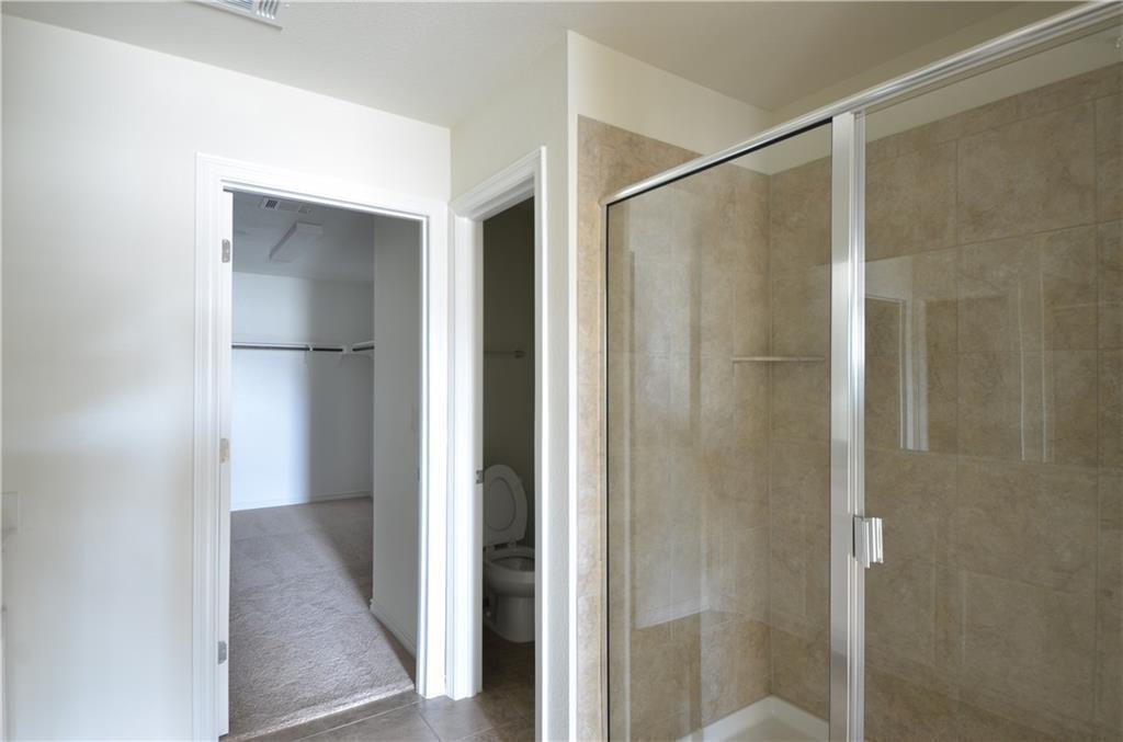 14403 McCoy Loop Austin, TX 78717 - Photo 21 of 29 Step into a well-appointed bathroom featuring a tiled shower enclosure with a glass door.