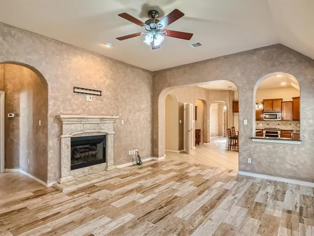 a view of a livingroom with a fireplace a ceiling fan and wooden floor