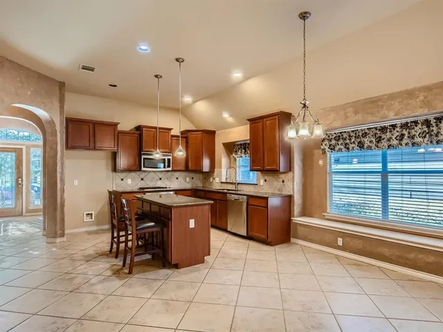 a kitchen with stainless steel appliances kitchen island granite countertop a sink a counter and chairs
