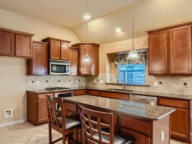 a kitchen with stainless steel appliances granite countertop a sink a stove and chairs