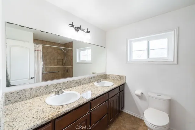 a bathroom with a granite countertop double vanity sink mirror and toilet