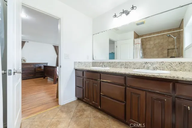 a en suite bathroom with a granite countertop sink and mirror