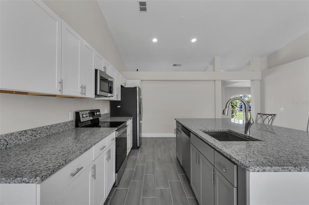 506 Peace Way Kissimmee, FL 34759 - Photo 11 of 34 a kitchen with granite countertop a sink a stove and cabinets