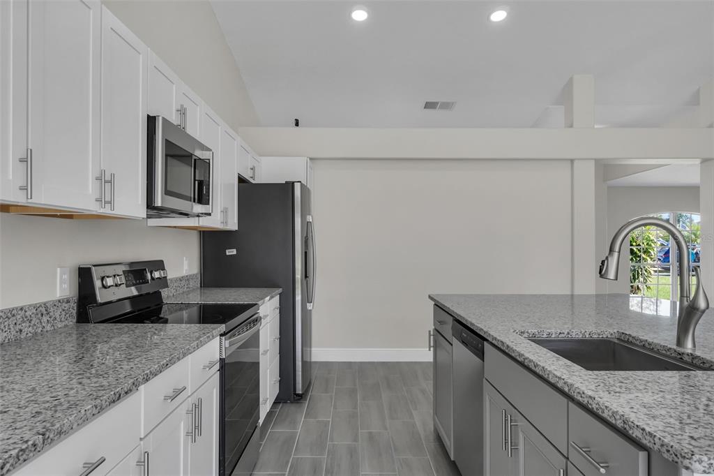 506 Peace Way Kissimmee, FL 34759 - Photo 12 of 34 a kitchen with granite countertop a sink a stove and refrigerator