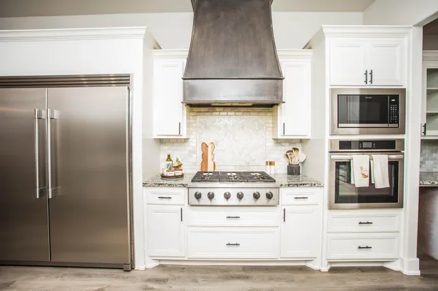 a kitchen with kitchen island granite countertop a sink a counter space appliances and cabinets