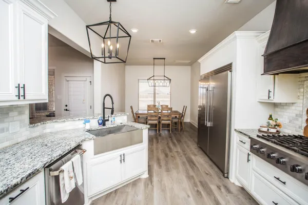 a kitchen with granite countertop a stove top oven a sink dishwasher and a refrigerator