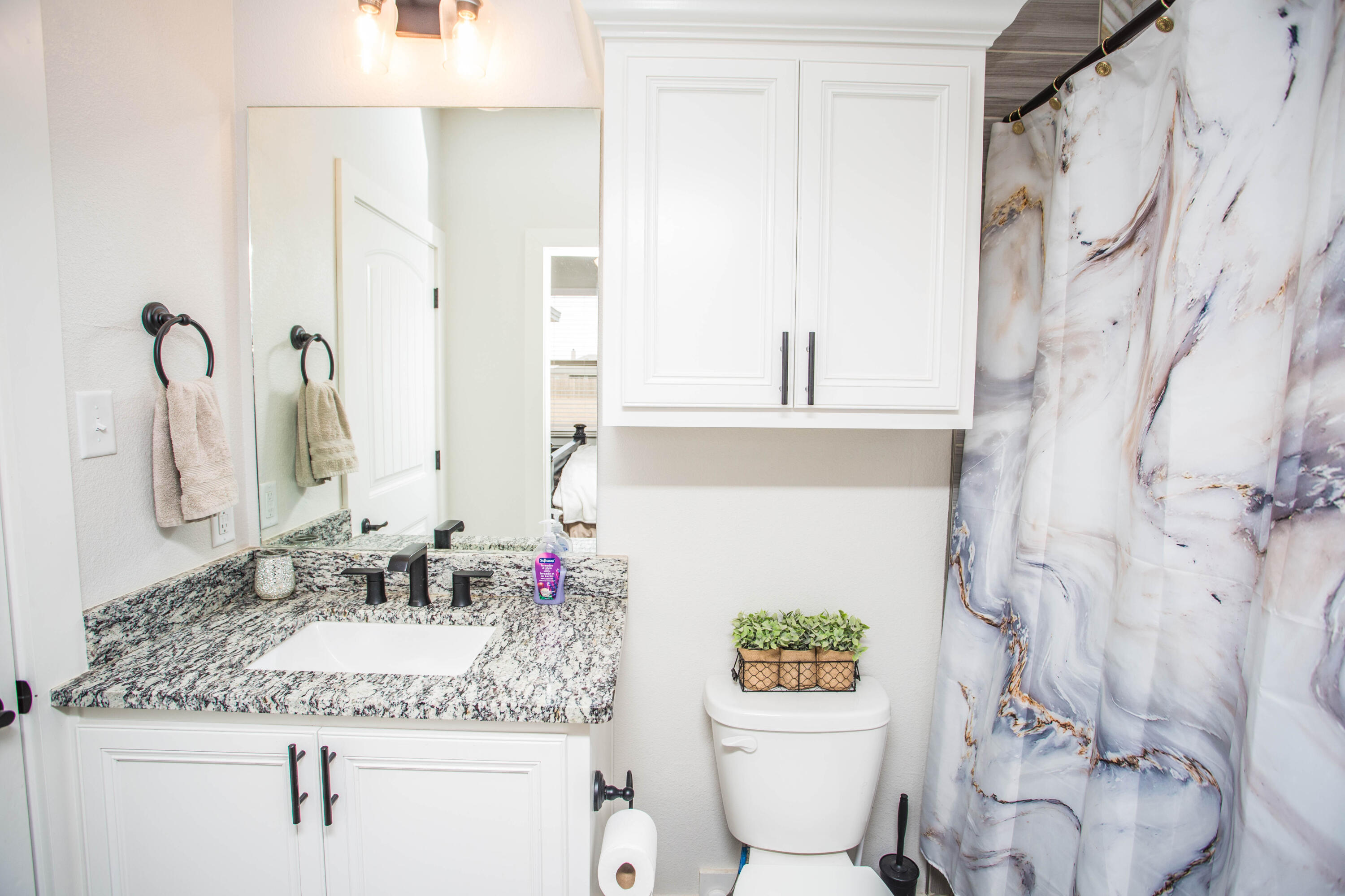 2204 County Road 7815 Lubbock, TX 79423 - Photo 42 of 58 a bathroom with a granite countertop sink a toilet and a mirror
