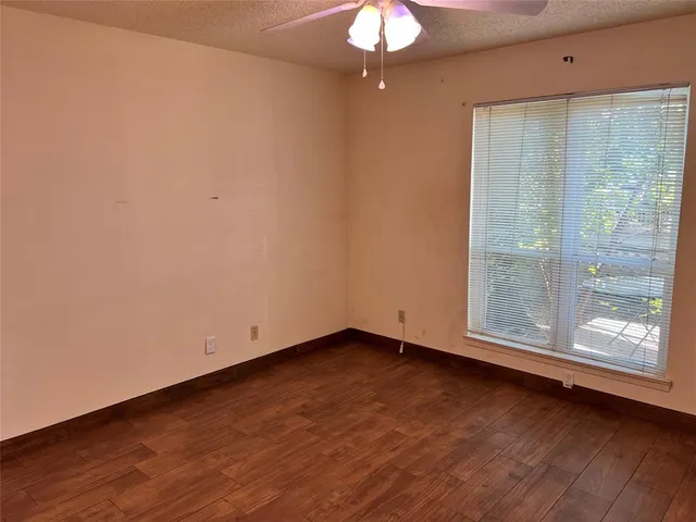 a view of a room with wooden floor and a ceiling fan