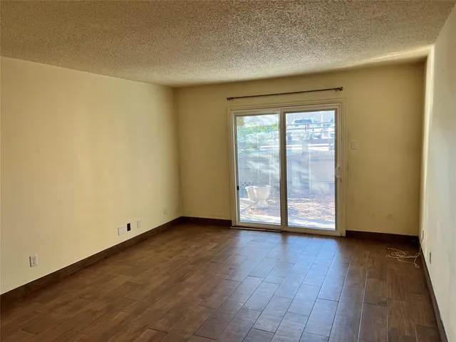 an empty room with wooden floor and a hallway