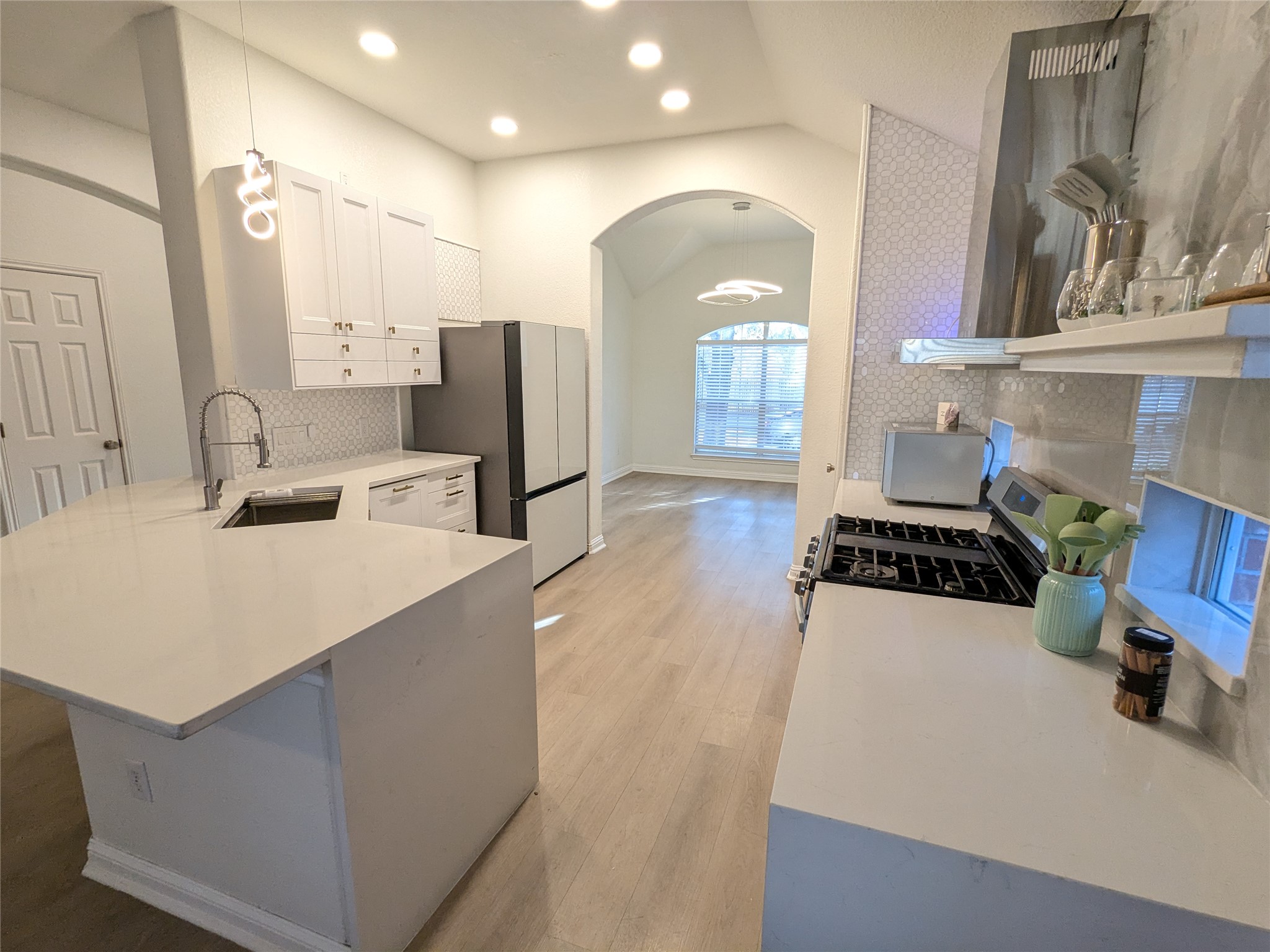a large white kitchen with sink a refrigerator and a stove top oven