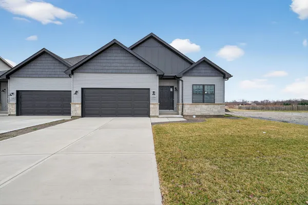 a front view of a house with a garden and lake view