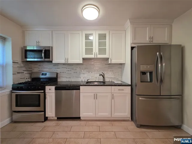 a kitchen with granite countertop a refrigerator and a stove top oven
