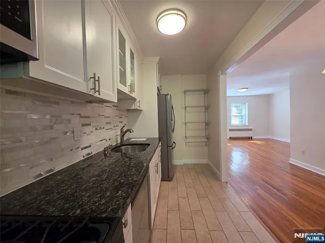 a kitchen with granite countertop stainless steel appliances and wooden floor