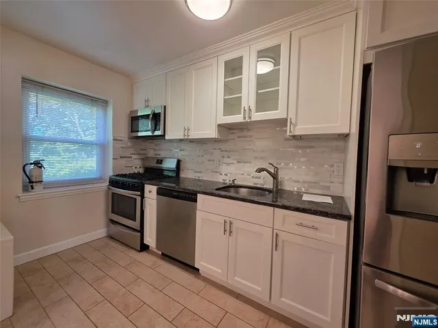 a kitchen with granite countertop a refrigerator stove and sink