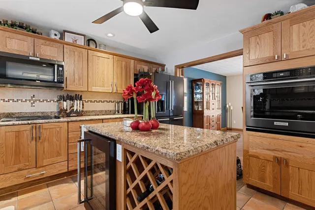 a kitchen with stainless steel appliances granite countertop a kitchen island a stove a sink dishwasher and microwave with wooden floor