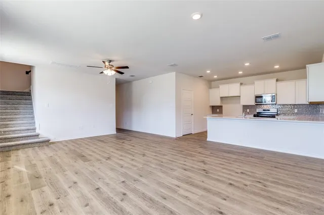 a view of kitchen with kitchen island a sink dishwasher and a refrigerator with wooden floor