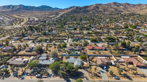 an aerial view of residential house with parking and mountain view in back
